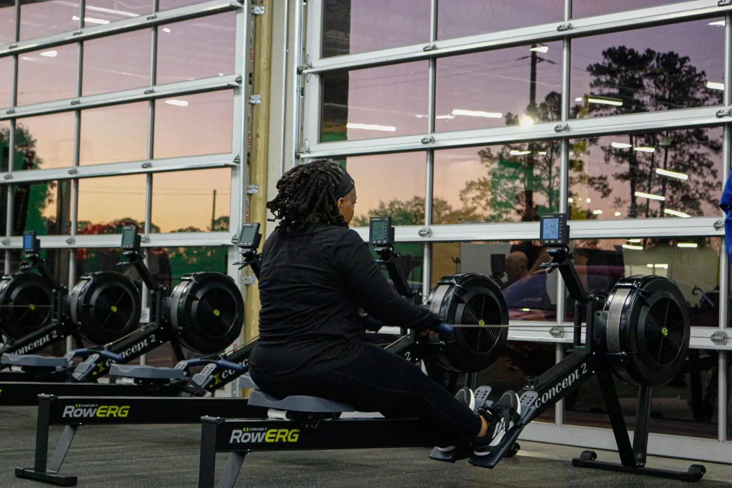 Member on a rowing machine by the glass garage doors at Downtown Gym