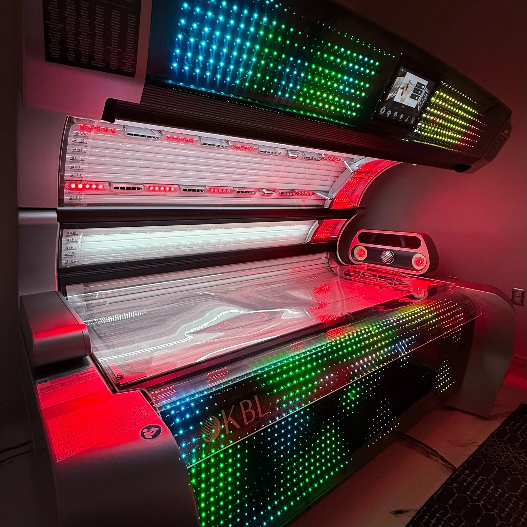 A Level 6 Diamond tanning bed at Downtown Gym, open and lit, with the red light lamps and LED trim on