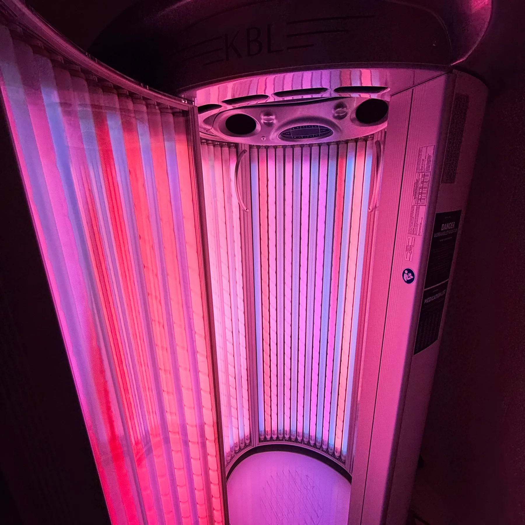 The KBL Hybrid Sun stand-up tanning booth at Downtown Gym, door open and the lamps lit, with nobody inside